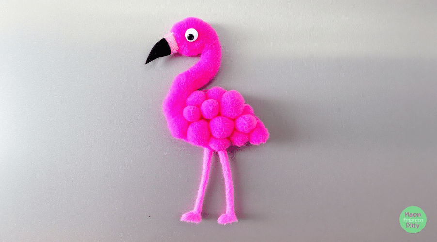 Pom pom flamingo magnet on a light grey background.