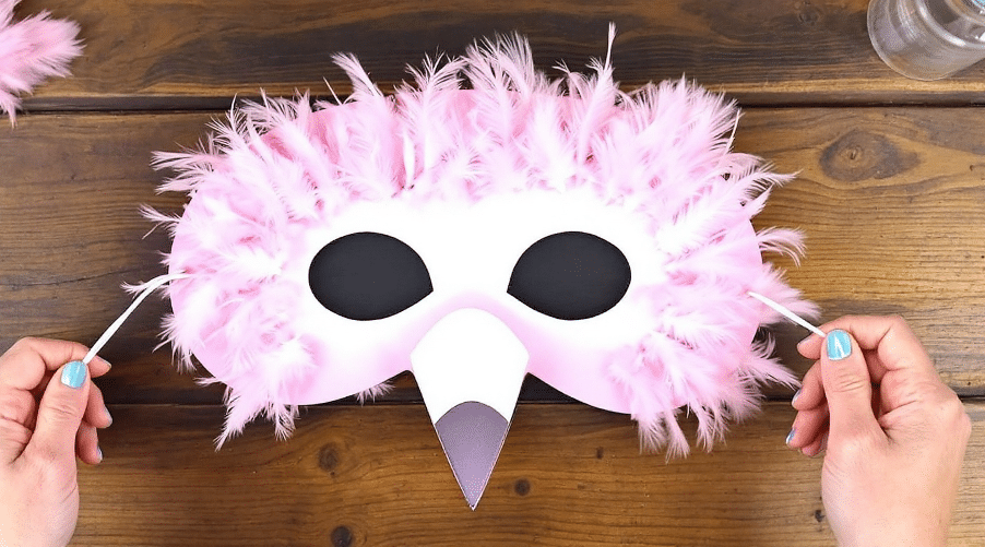 A mask designed like a flamingo on a wooden table.