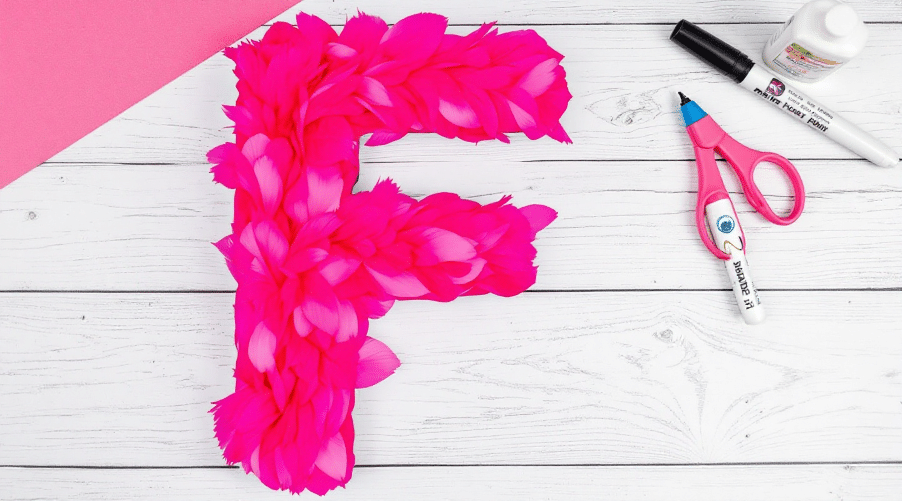 A large f letter with pink materials.