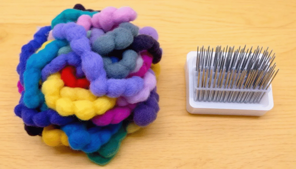 The image showcases a work surface filled with needle felting supplies, including colorful wool roving and various felting needles, inviting creativity and exploration for both beginners and experienced crafters. This arrangement of materials reflects the fun and imaginative process of crafting, perfect for creating unique projects or special presents.
