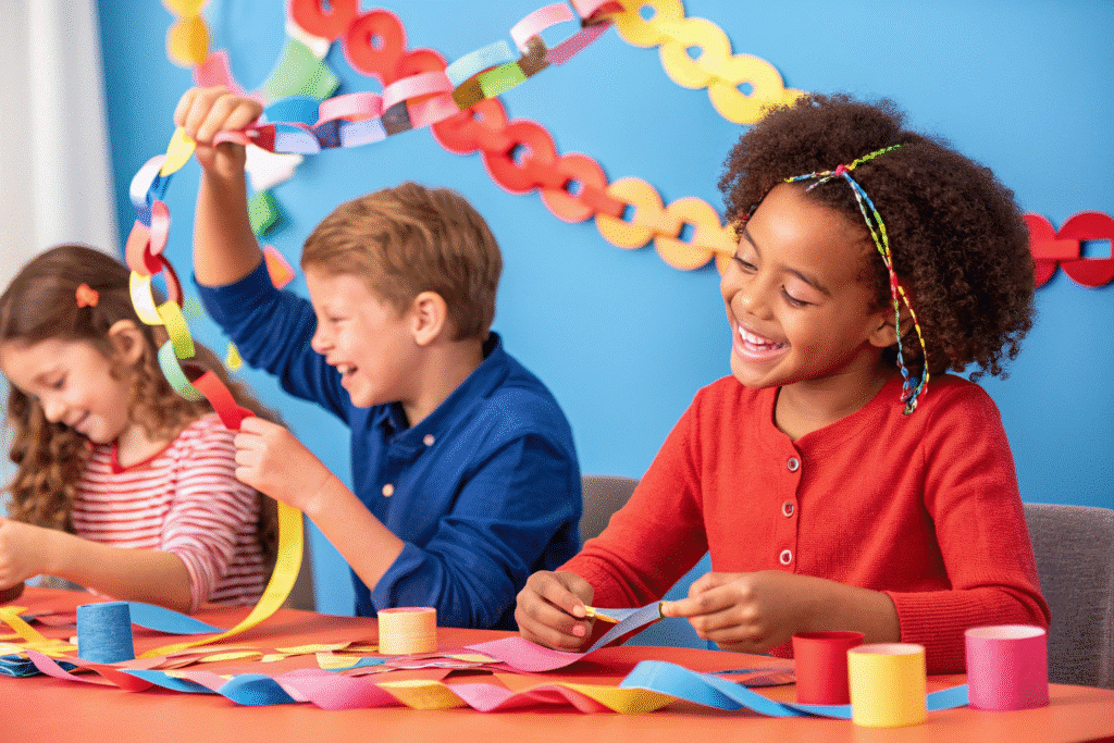 In the image, a group of children joyfully sits around a table, engaged in making colorful paper chain decorations using scissors and glue, showcasing a fun paper craft activity. The vibrant chains created from patterned and construction paper add a festive touch to their creative project.