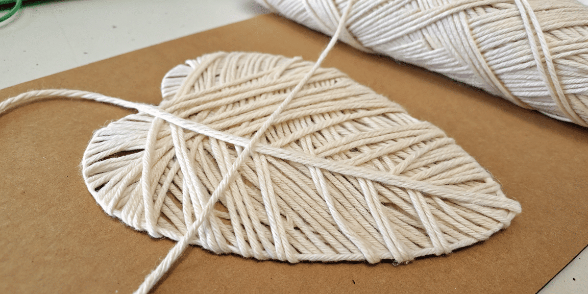 48fba7fea99d432b801b793cb5194806 simply paper crafts A photo of a close up view of a bundle of white rope artfully tied into a heart shape on a brown textured paper like surface