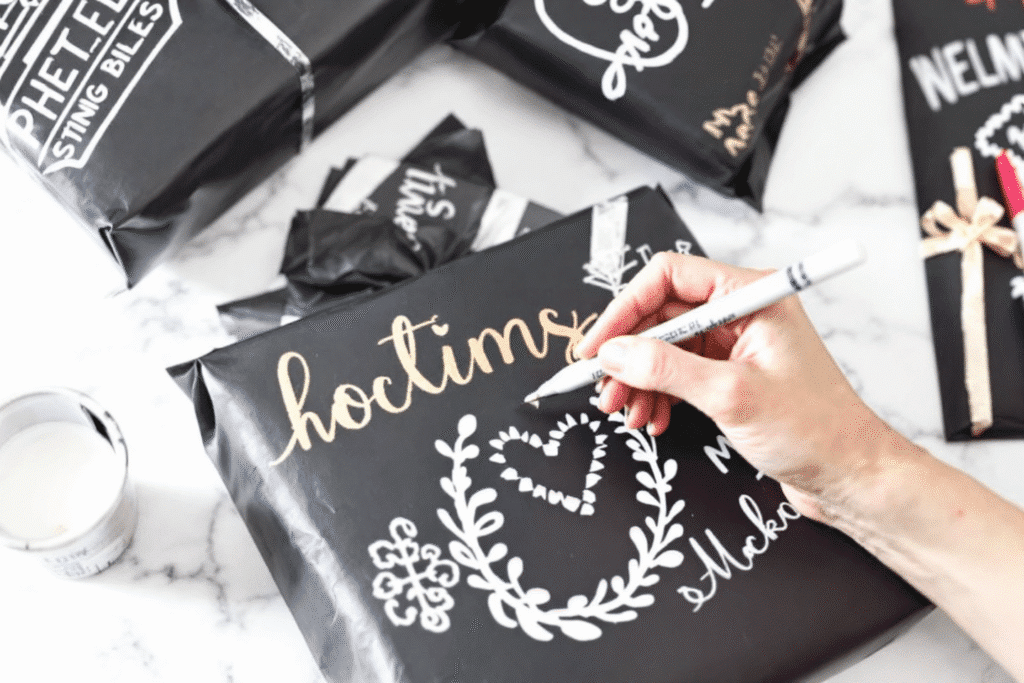 Image simply paper crafts A person using a white marker to draw on a black wrapped gift