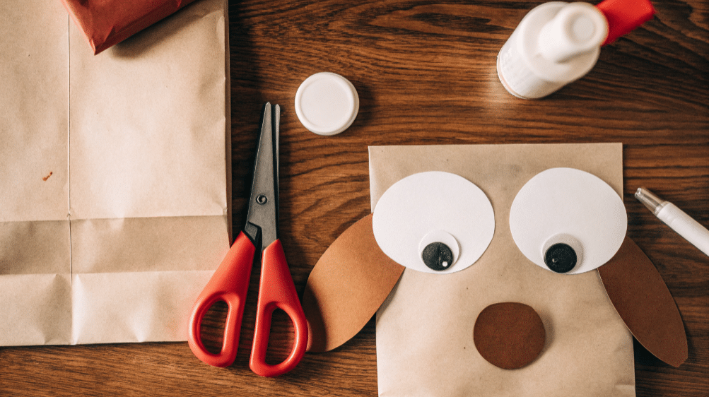 Basic supplies for your dog puppet simply paper crafts The image shows a collection of craft supplies for creating a dog paper bag puppet including a brown paper bag scissors glue crayons white construction paper googly eyes and colored paper for details like ears and a collar This setup is perfect for kids' crafts, especially for making a fun and adorable paper bag dog craft.