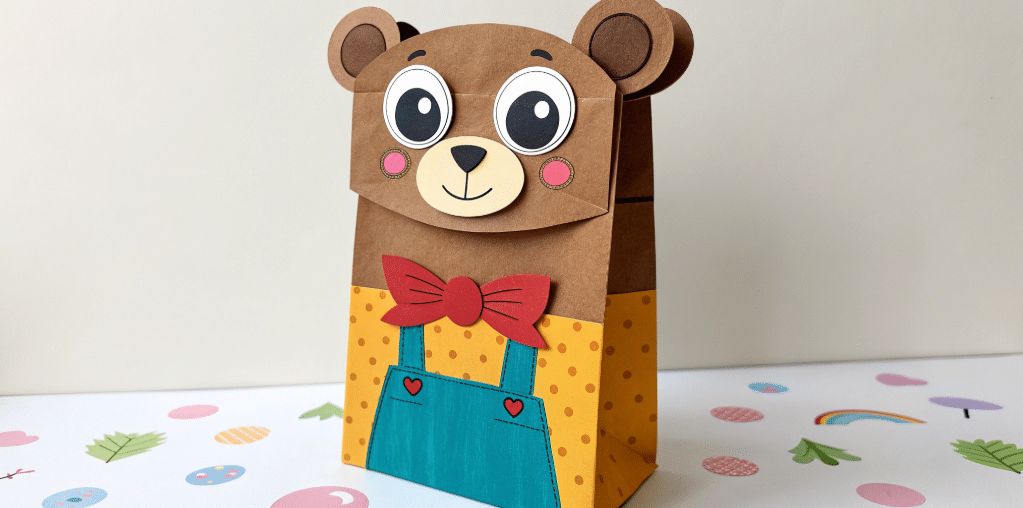 Paper bear bag character simply paper crafts The image showcases a colorful and adorable paper bag bear puppet crafted from a simple paper bag construction paper and googly eyes This fun activity is designed for kids to enhance their fine motor skills while using their creativity to create unique and cute bear puppets for storytelling or playtime