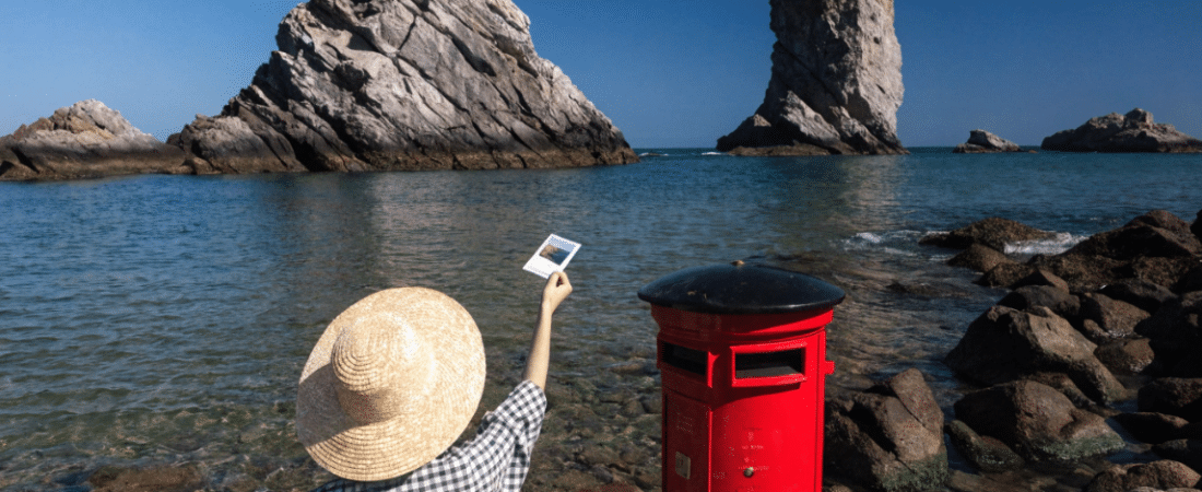 Send a postcard to a friend A person posting a postcard in a letter box