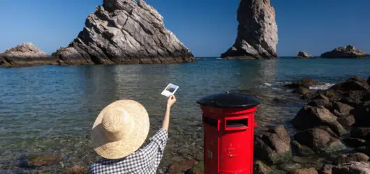 A person posting a postcard in a letter box